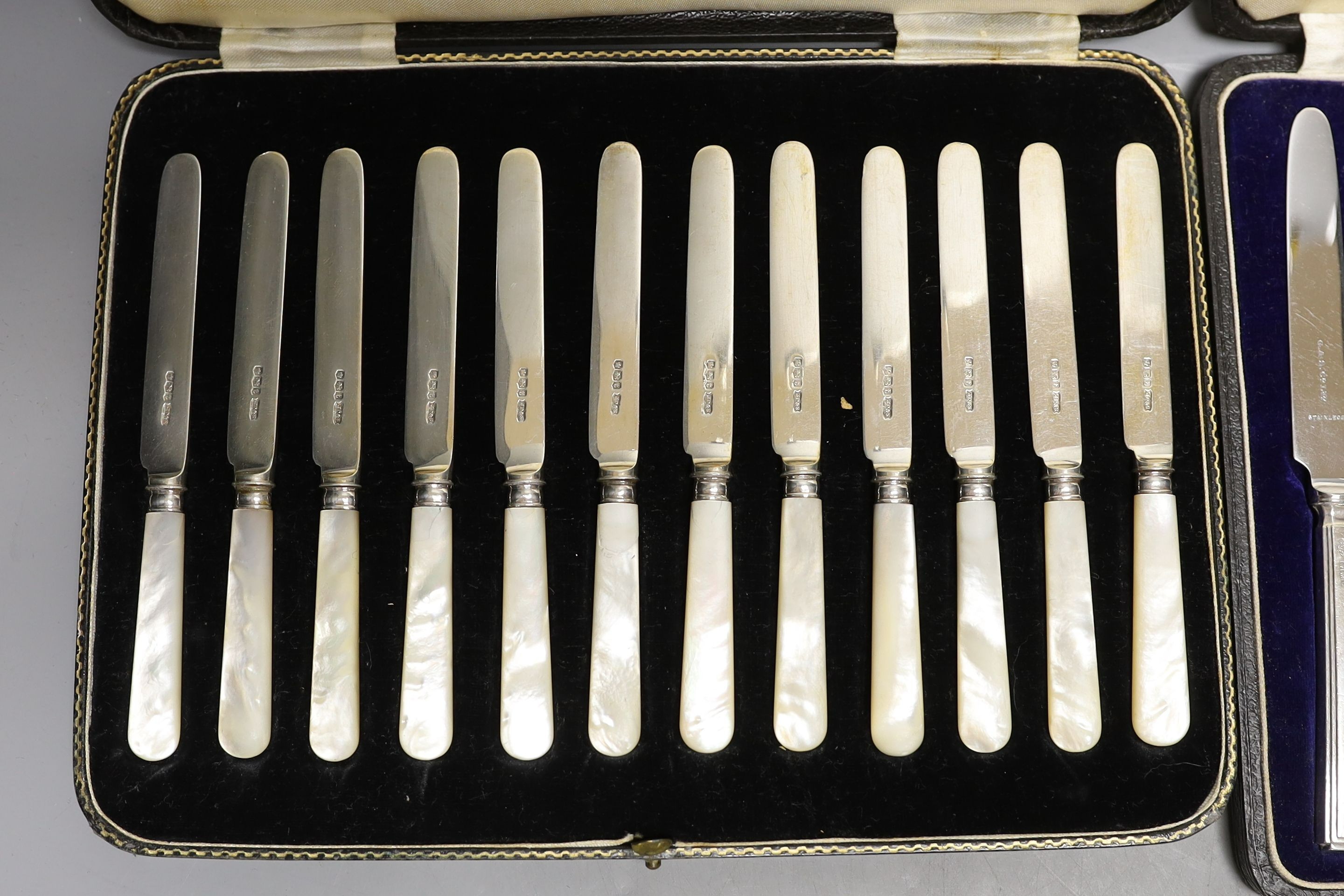 Two cased sets of silver or mother of pearl handled tea knives and a cased set of six silver teaspoons.